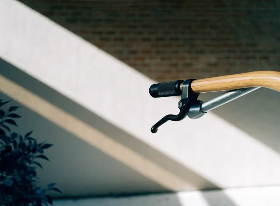 A bike brake lever on a handlebar in front of a brick wall